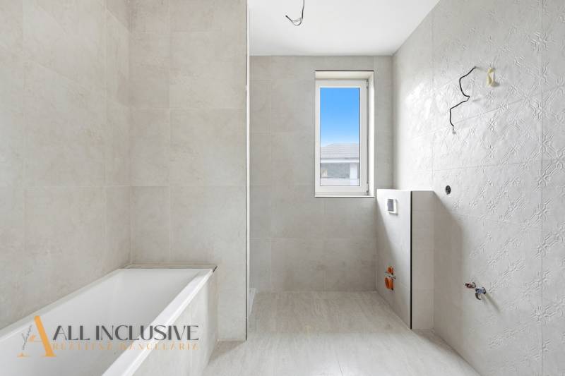 Fürdőszoba családi házban káddal, ablakkal és világos csempékkel.