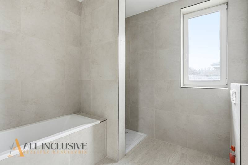 Fürdőszoba családi házban káddal, zuhanyzóval és függöny nélküli ablakkal.