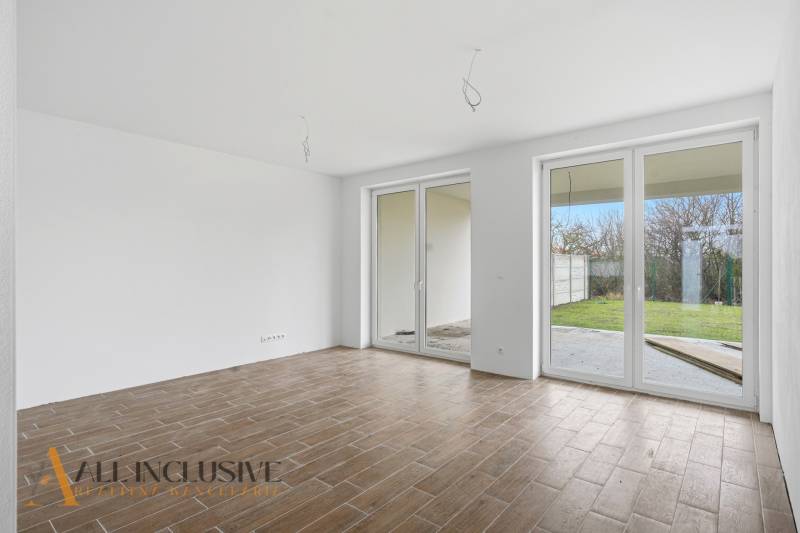 Szoba egy családi házban, fa dekoros padlóval és francia ablakokkal.