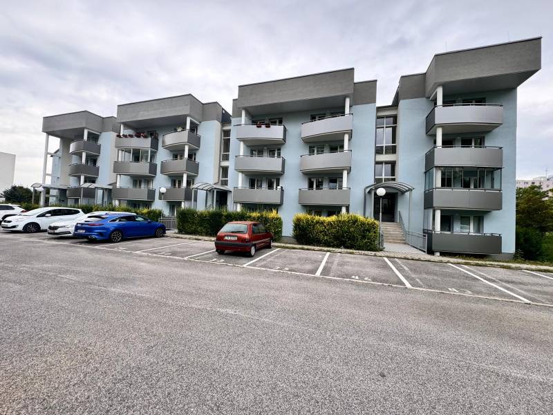 Tömbház szürke erkélyekkel a Halalovkán, Trencsénben, parkolóhelyekkel.