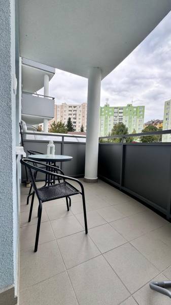 Erkély egy kétszobás lakásban a Halalovkán, Trencsénben, asztallal és székekkel, kilátással a panelházakra.