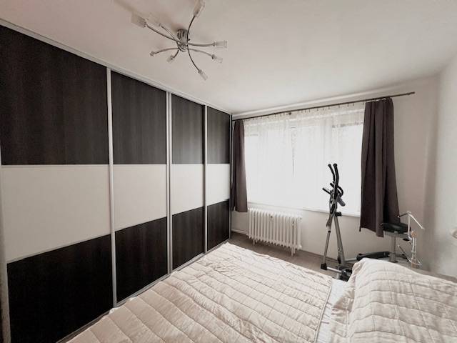 Hálószoba egy kétszobás lakásban nagy ruhásszekrénnyel és edzőfelszereléssel.