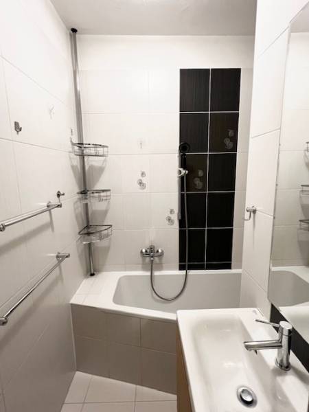 Fürdőszoba egy kétszobás lakásban zuhanyzóval és fehér csempékkel.