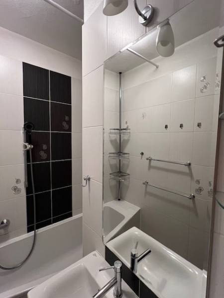 Fürdőszoba egy kétszobás lakásban káddal, mosdóval és világos csempékkel.