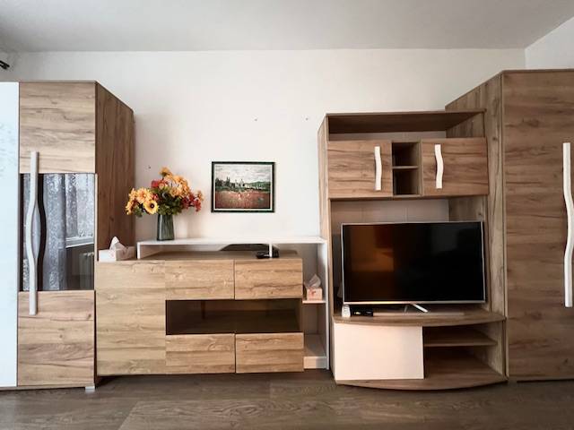 Nappali egy kétszobás lakásban, fa mintázatú padlóval és bútorokkal.