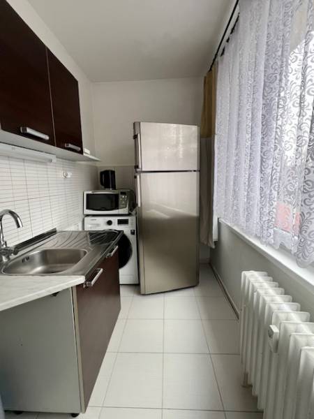 Konyha egy kétszobás lakásban fehér csempével, mosogatóval és háztartási gépekkel.