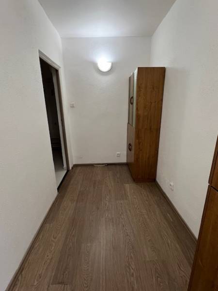 Folyosó egy 2 szobás lakásban fa dekor padlóval és bútorokkal.