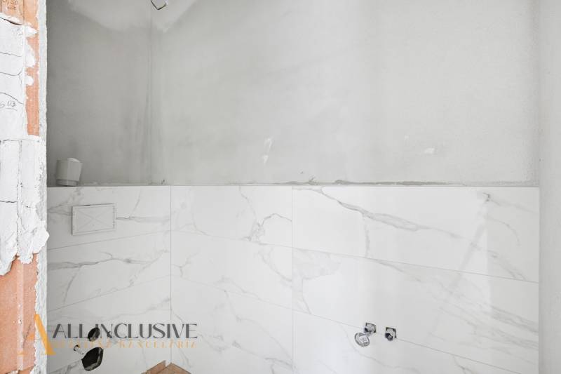 Fürdőszoba családi házban fehér márvány burkolatokkal, berendezési tárgyak nélkül.