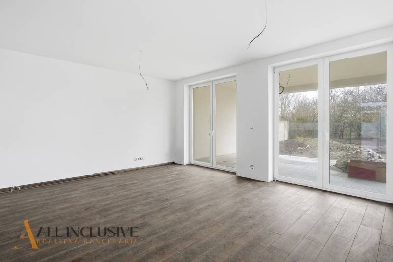 Tágas szoba egy családi házban nagy ablakokkal és fa dekorációjú padlóval.