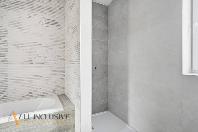 Fürdőszoba családi házban káddal és zuhanyzóval, világos csempékkel.