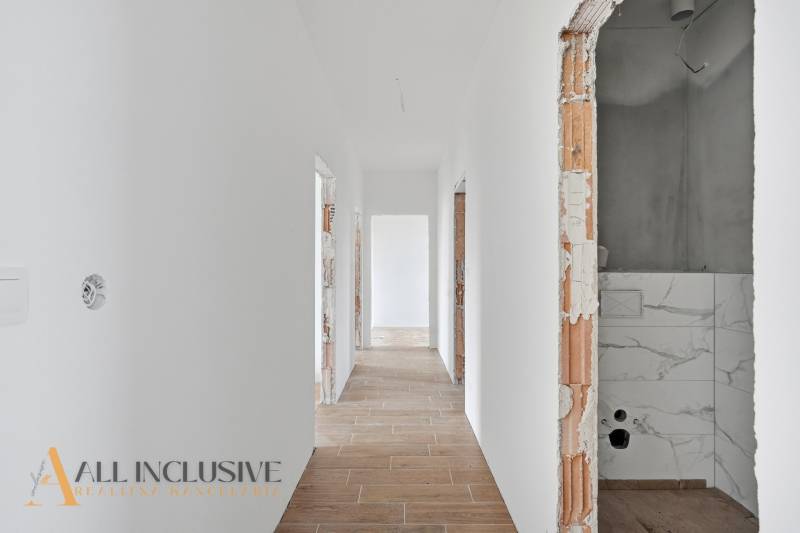 Egy családi ház folyosója fehér falakkal és fa dekorációjú padlóval.