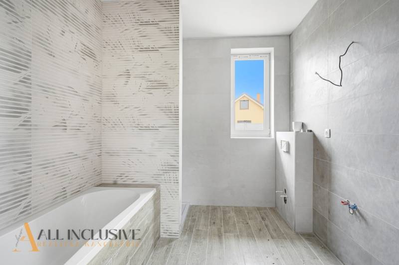 Fürdőszoba családi házban káddal, szürke csempékkel és fa mintázatú padlóval.