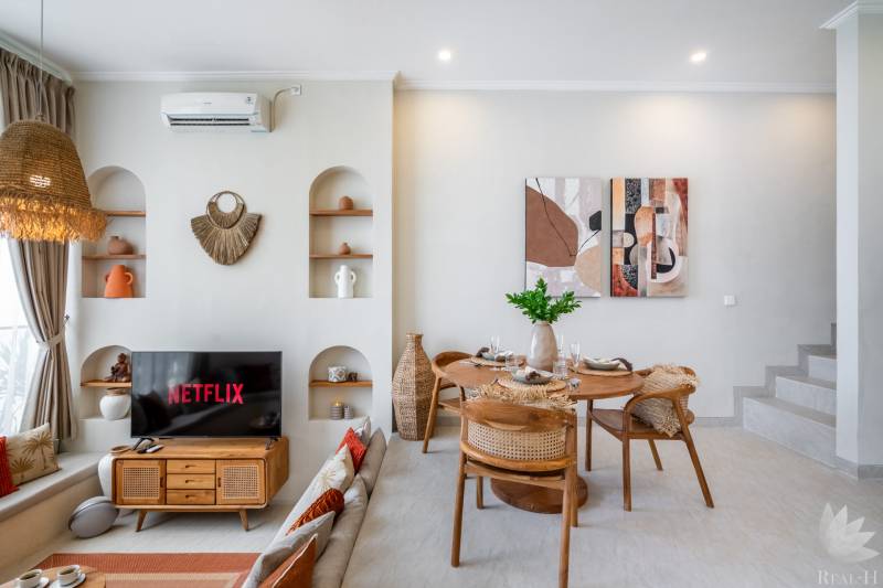 A villa nappalija TV-vel, étkezőasztallal és dekorációs elemekkel a falakon.