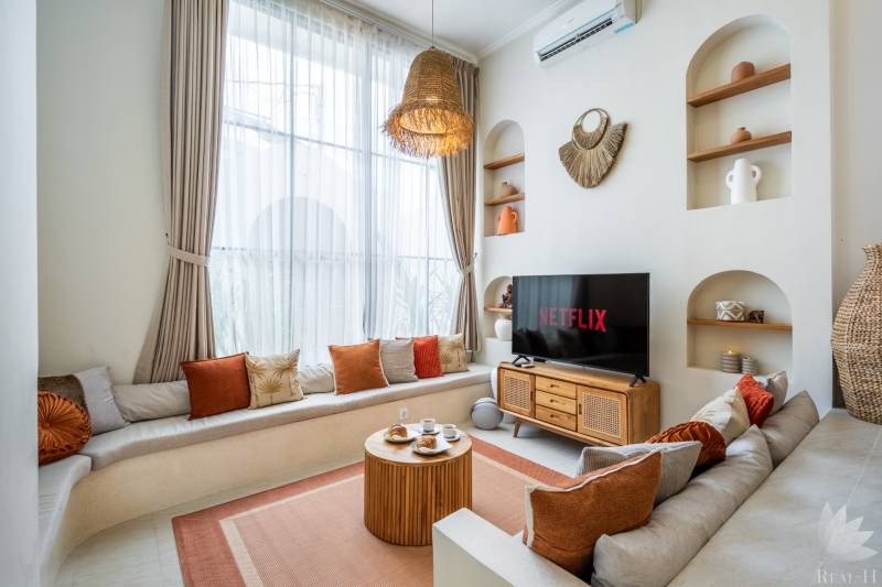 Vilabeli világos nappali kanapéval, TV-vel és dekoratív világítással.