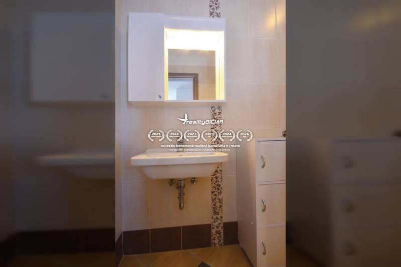 Fürdőszoba mosdóval, tükörrel és tárolószekrénnyel egy kétszobás lakásban.