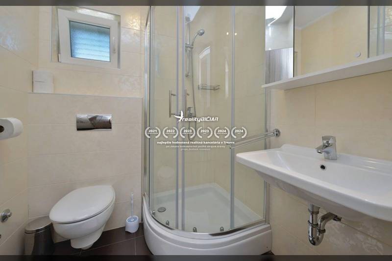 Fürdőszoba egy kétszobás lakásban WC-vel, zuhanyzóval és mosdóval.