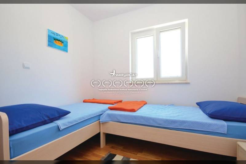 Világos szoba két egyszemélyes ággyal és fa dekorációjú padlóval.