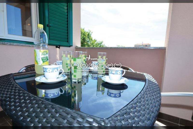 A 2 szobás lakás erkélye fonott asztallal, teáskészlettel és kilátással Privlakára.