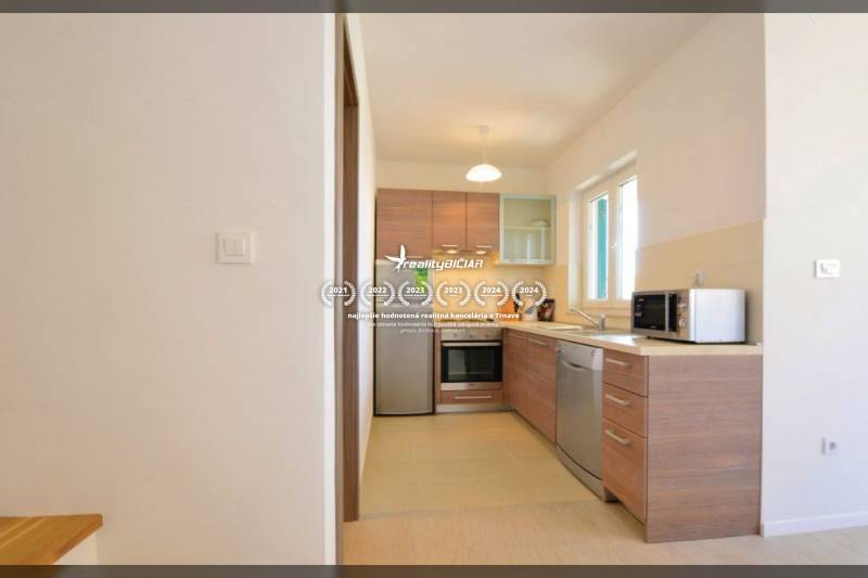 Konyha egy kétszobás lakásban fa dekorációval és készülékekkel, világos színekben.