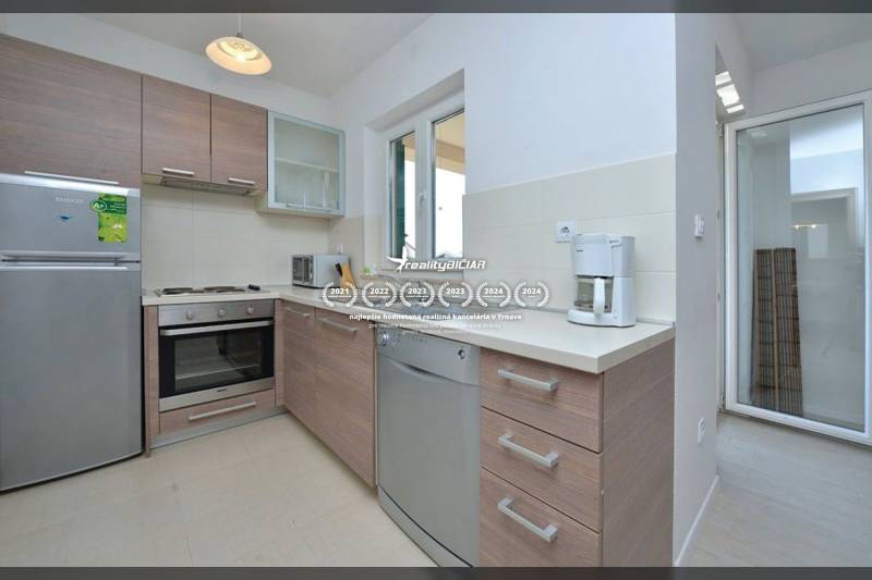 Konyha egy kétszobás lakásban, fa dekorációjú berendezéssel és padlóval.