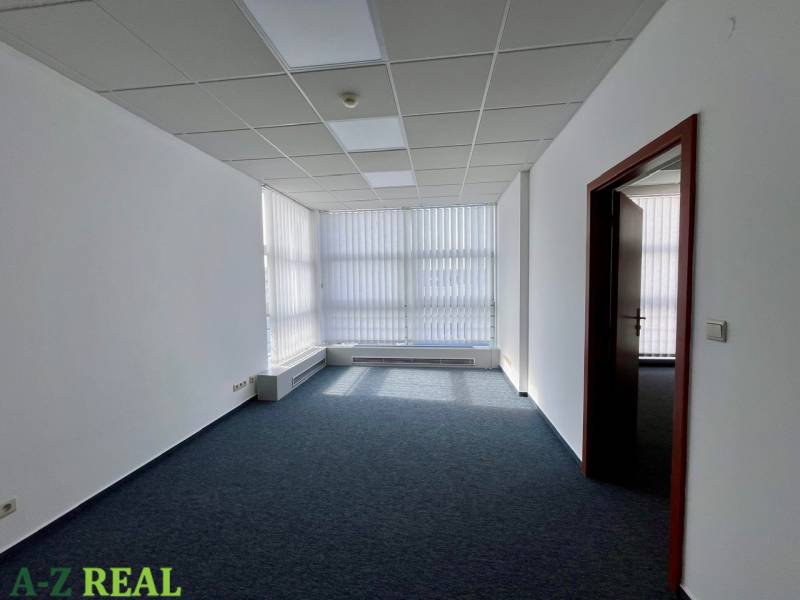 Irodák szőnyegpadlóval, fehér falakkal és redőnyökkel az ablakokon.