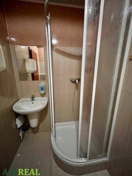 Zuhanykabin és mosdó a bérbe adott irodák fürdőszobájában.