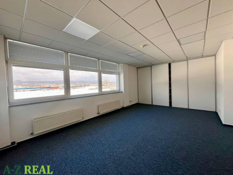 Irodák nagy ablakokkal és szőnyegpadlóval, kilátással a városra.