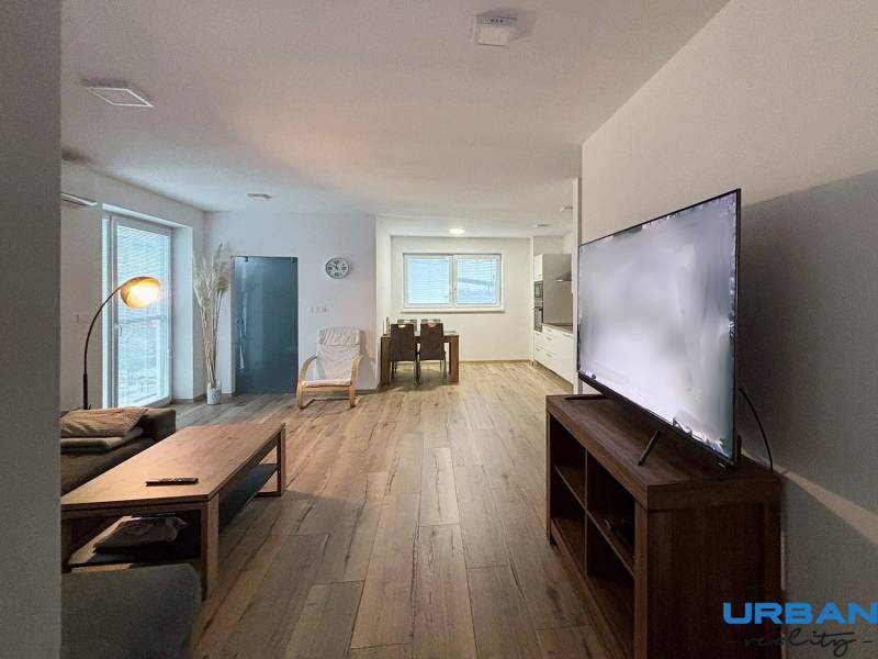 Nappali egy háromszobás lakásban kanapéval, televízióval és fa dekorációjú padlóval.