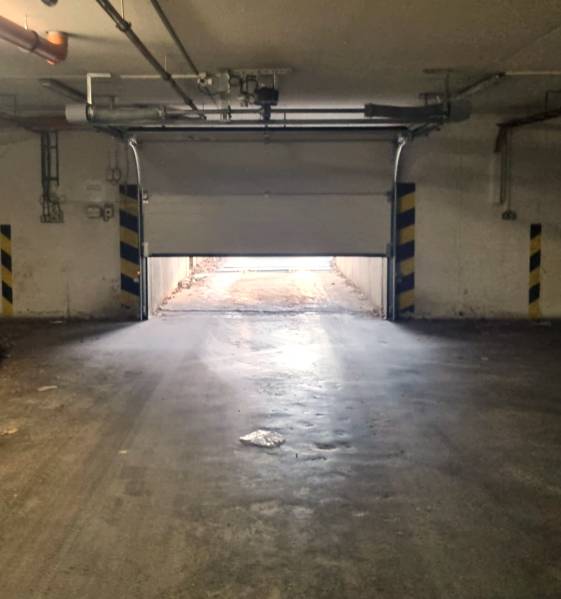 A félig nyitott garázskapu kivezet, a környezetet közvetett fény világítja meg.