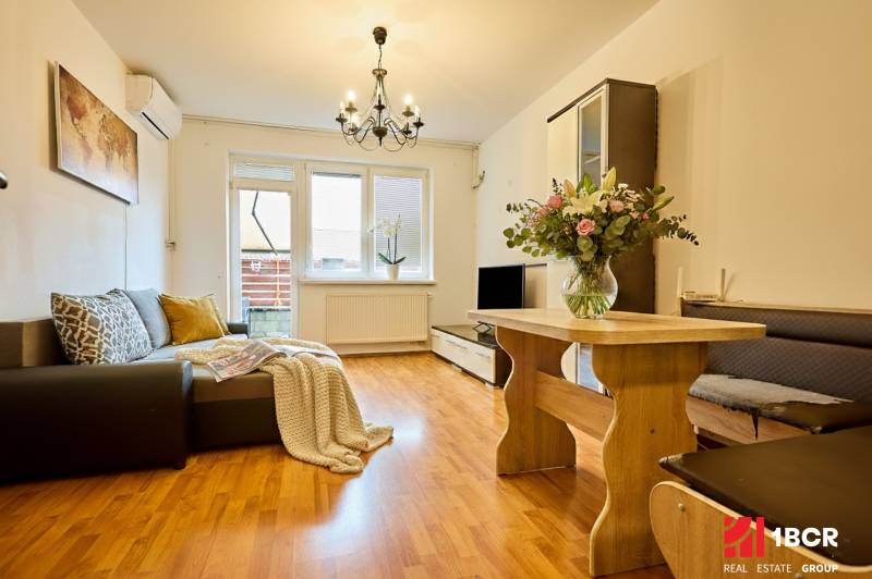 Nappali egy kétszobás lakásban fa dekorációjú padlóval és kanapéval.