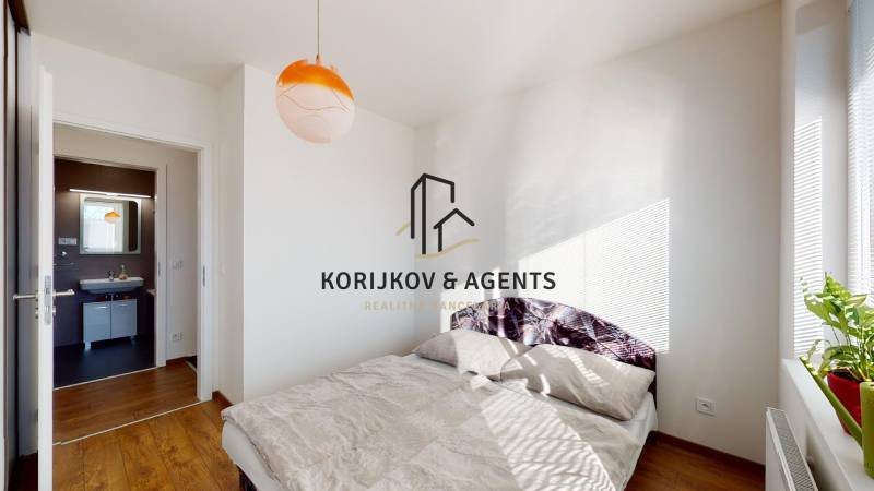 Kétszobás lakás hálószobája ággyal és fa dekorációjú padlóval.