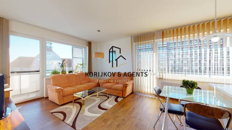 Nappali egy kétszobás lakásban, fa mintázatú padlóval és kényelmes kanapéval.