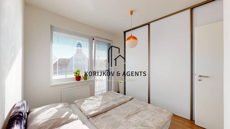 Hálószoba tolóajtós szekrénnyel és ággyal egy kétszobás lakásban, fa dekoros padlóval.