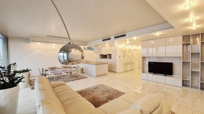 3 szobás lakás belső tere nyitott konyhával és fehér ülőgarnitúrával.