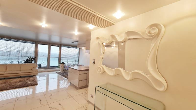 Luxusos belső tér háromszobás lakásban nagy ablakokkal és stílusos tükörrel.