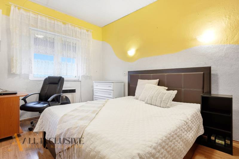 Hálószoba családi házban ággyal, székkel és fa dekoros padlóval.