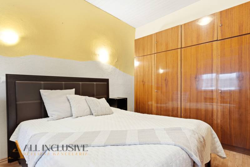 Hálószoba ággyal és beépített szekrénnyel, családi ház. Semleges színek, fa dekorációjú padló.