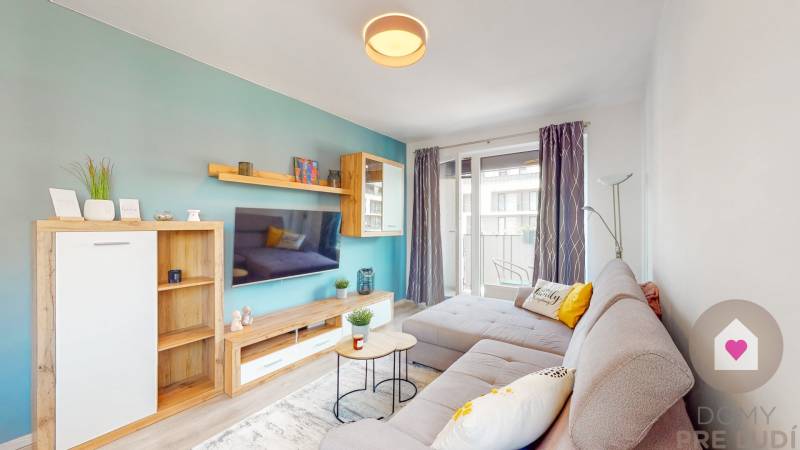 Nappali egy háromszobás lakásban kényelmes kanapéval és erkéllyel, fa dekorációjú padlóval.