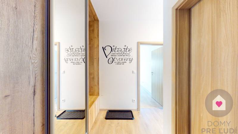 Előszoba fa dekor padlóval egy háromszobás lakásban, és felirat a falon.