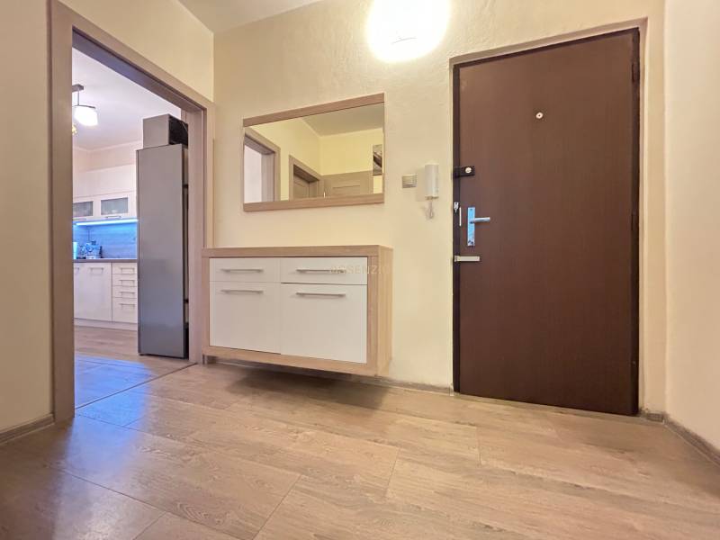 A kétszobás lakás folyosója fa dekorációjú padlóval és kilátással a konyhára.