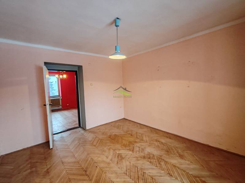 Szoba egy kétszobás lakásban, fa dekorú padlóval és egyszerű világítással.