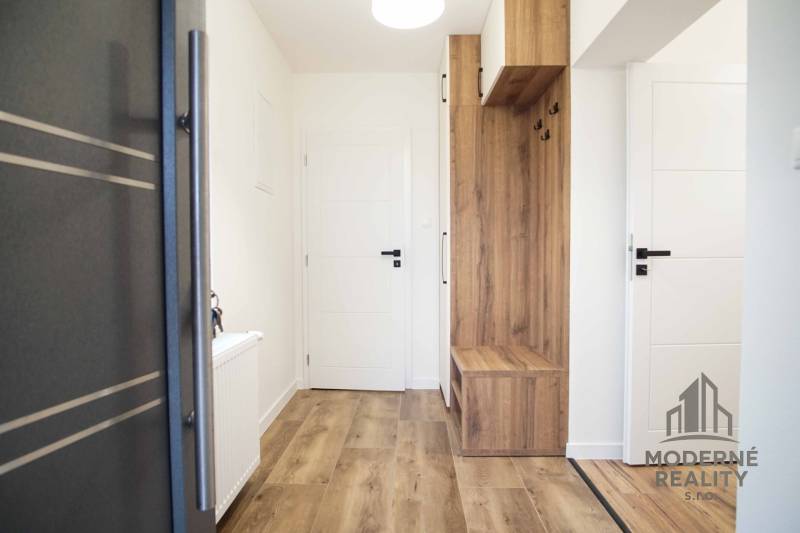 Családi ház belső tere fa mintázatú padlóval és beépített bútorokkal.