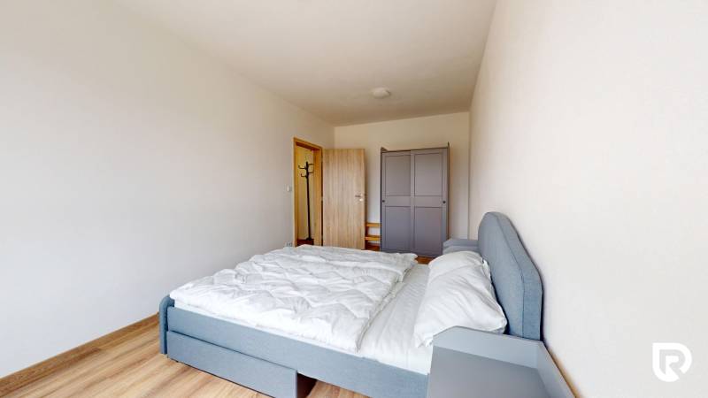 Hálószoba egy háromszobás lakásban ággyal, gardróbbal és fa dekorációjú padlóval.