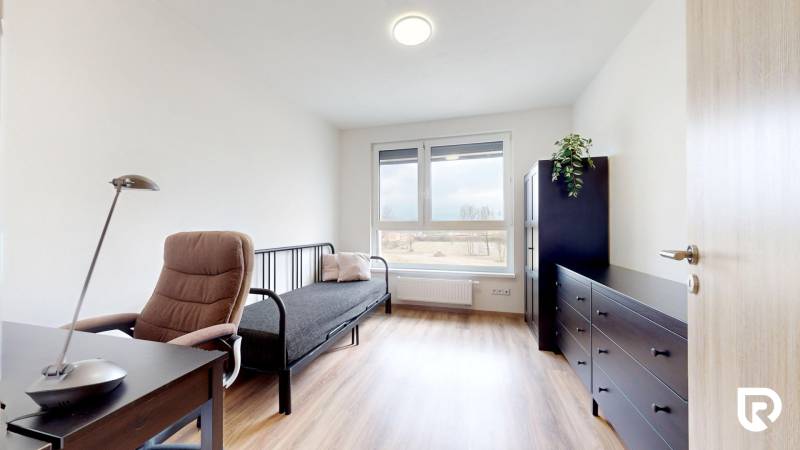 Szoba fa mintázatú padlóval, íróasztallal és kanapéval egy háromszobás lakásban.