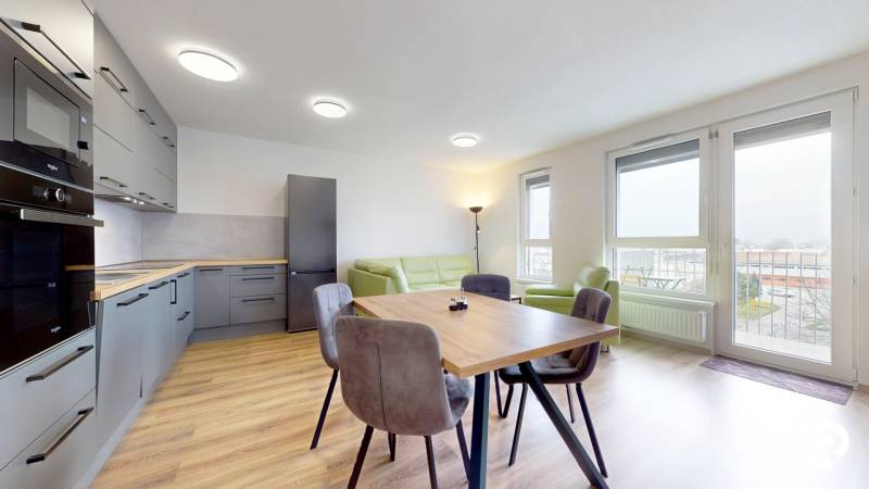 Konyha fa hatású padlóval és étkezőasztallal egy háromszobás lakásban.