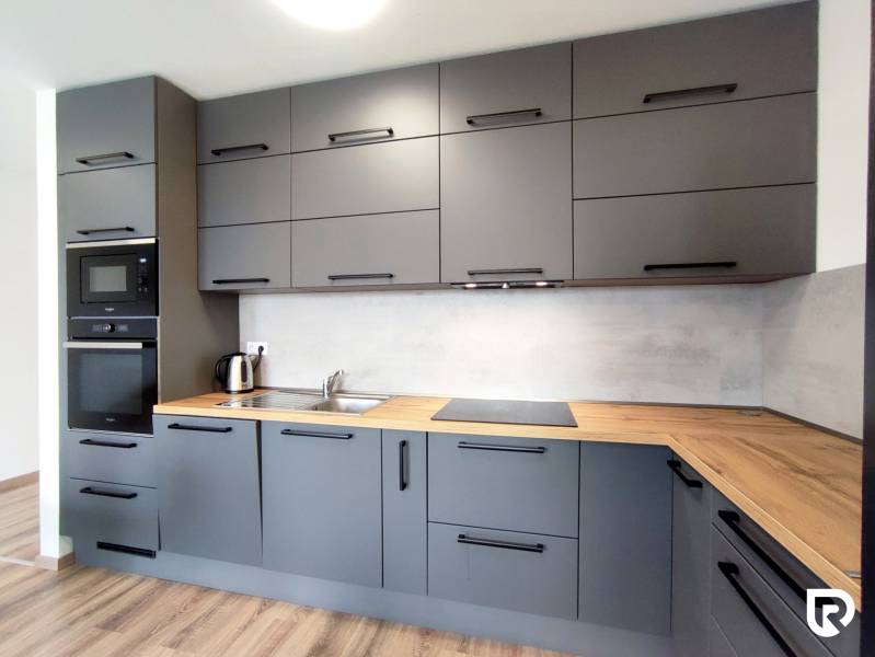 Stílusos konyha egy háromszobás lakásban, fa hatású padlóval és szürke szekrényekkel.