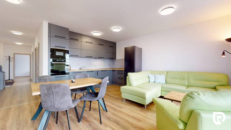 Konyha nappalival a háromszobás lakásban, zöld kanapé, fa dekorú padló.