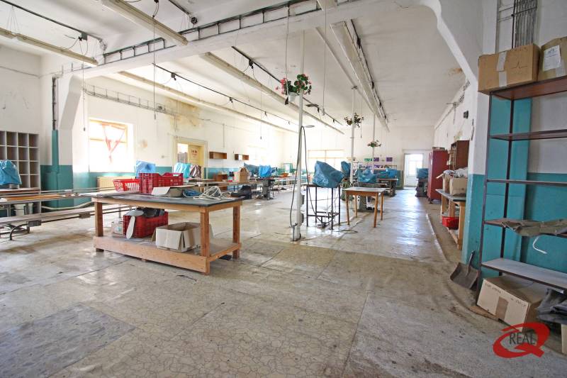 Az épület belső tere nagy csarnokkal, munkaasztalokkal és polcokkal.