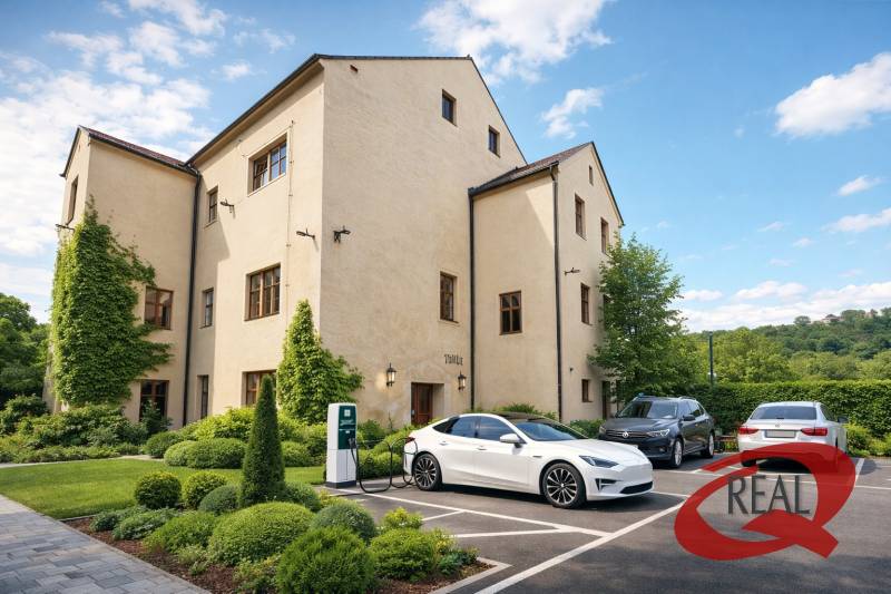 Épület Nagyugrócban zöldterülettel és elektromos autók töltőállomásával a parkolóban.