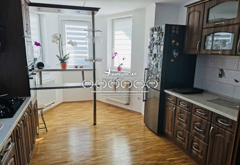 Konyha egy családi házban, fa dekoros padlóval, sötét bútorokkal és bárpulttal.